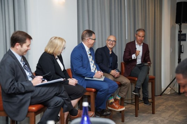 A panel of five professionals seated on stools during a discussion.