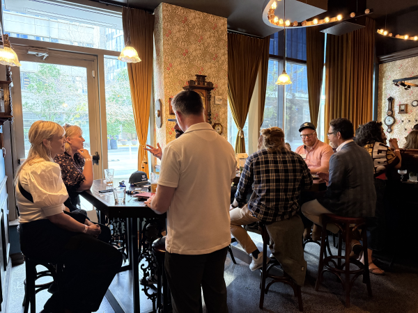 A group of people socializing around a high table in a bar setting.
