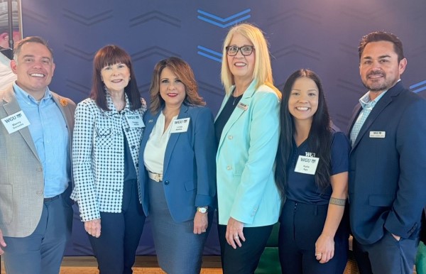 A group of six people, dressed in business attire, posing for a photo.