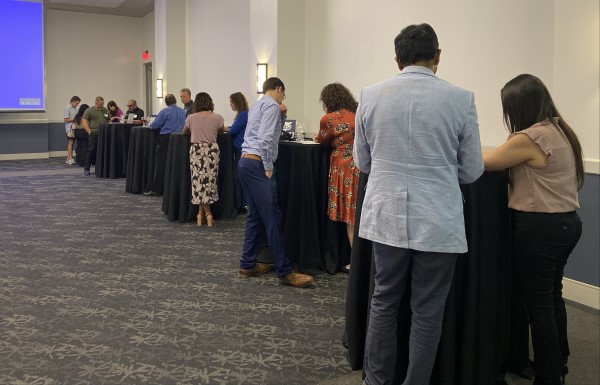 Attendees networking around tall tables at an event.