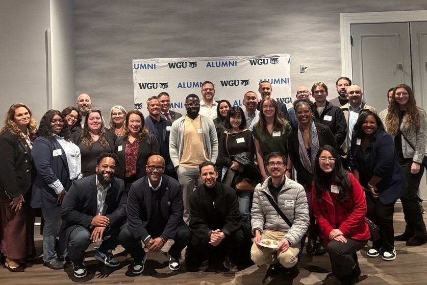 A diverse group of WGU alumni smiling and posing for a photo at an event.