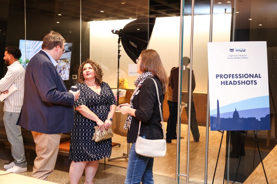 Attendees at a professional networking event, with a sign advertising 'Professional Headshots' and a photography setup in the background.