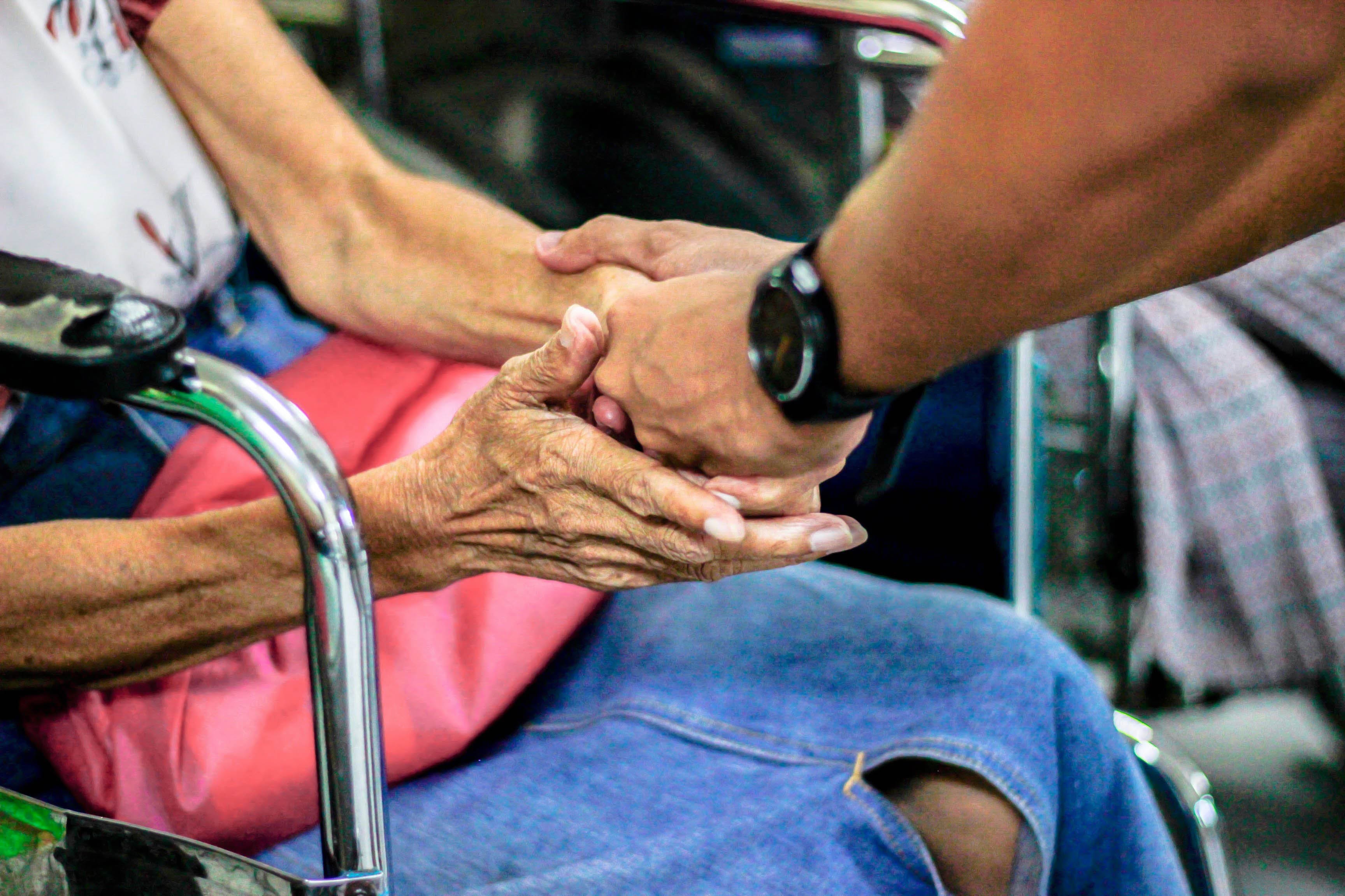 Man holding hand of woman in wheelchair