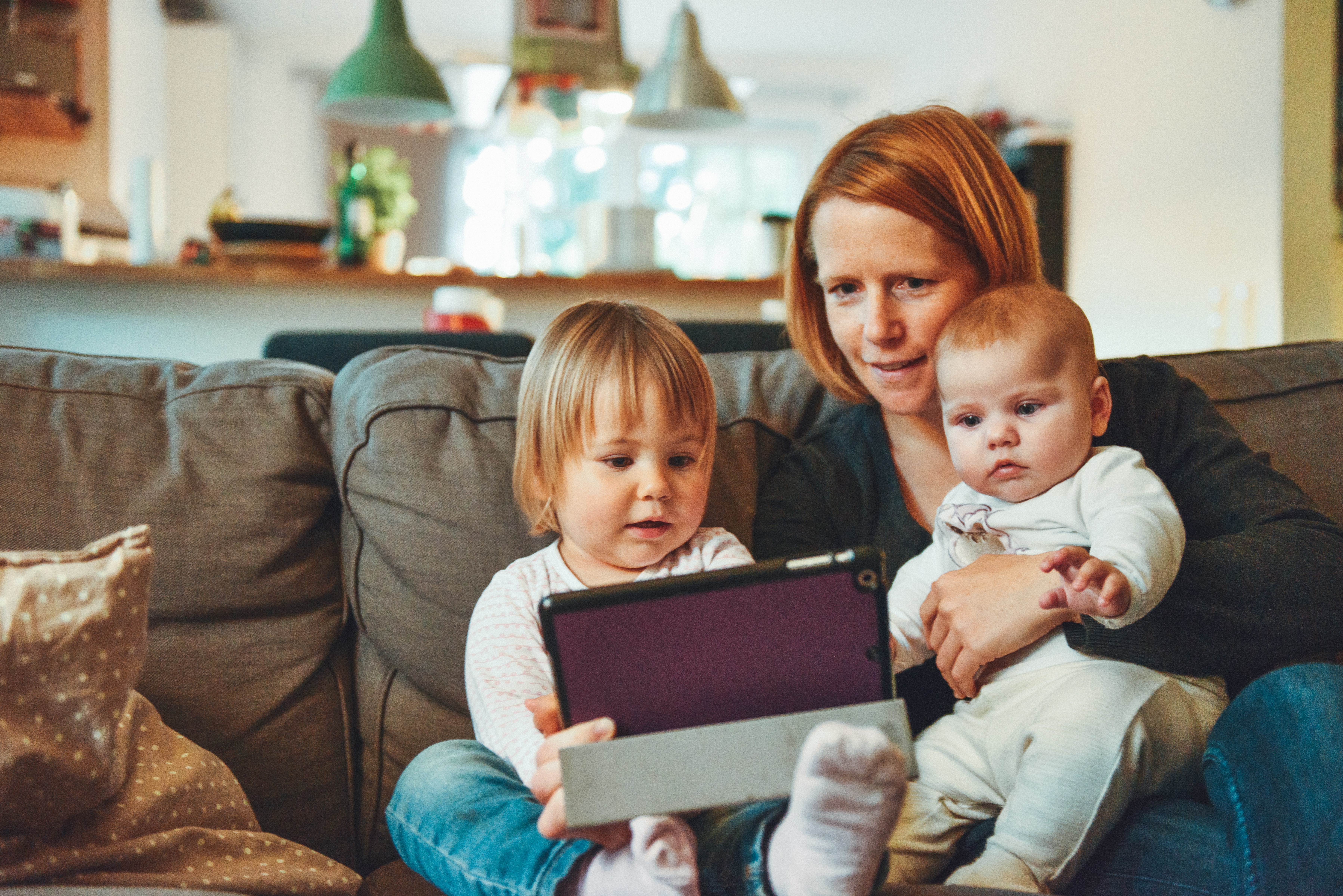 Woman with toddler and baby on couch