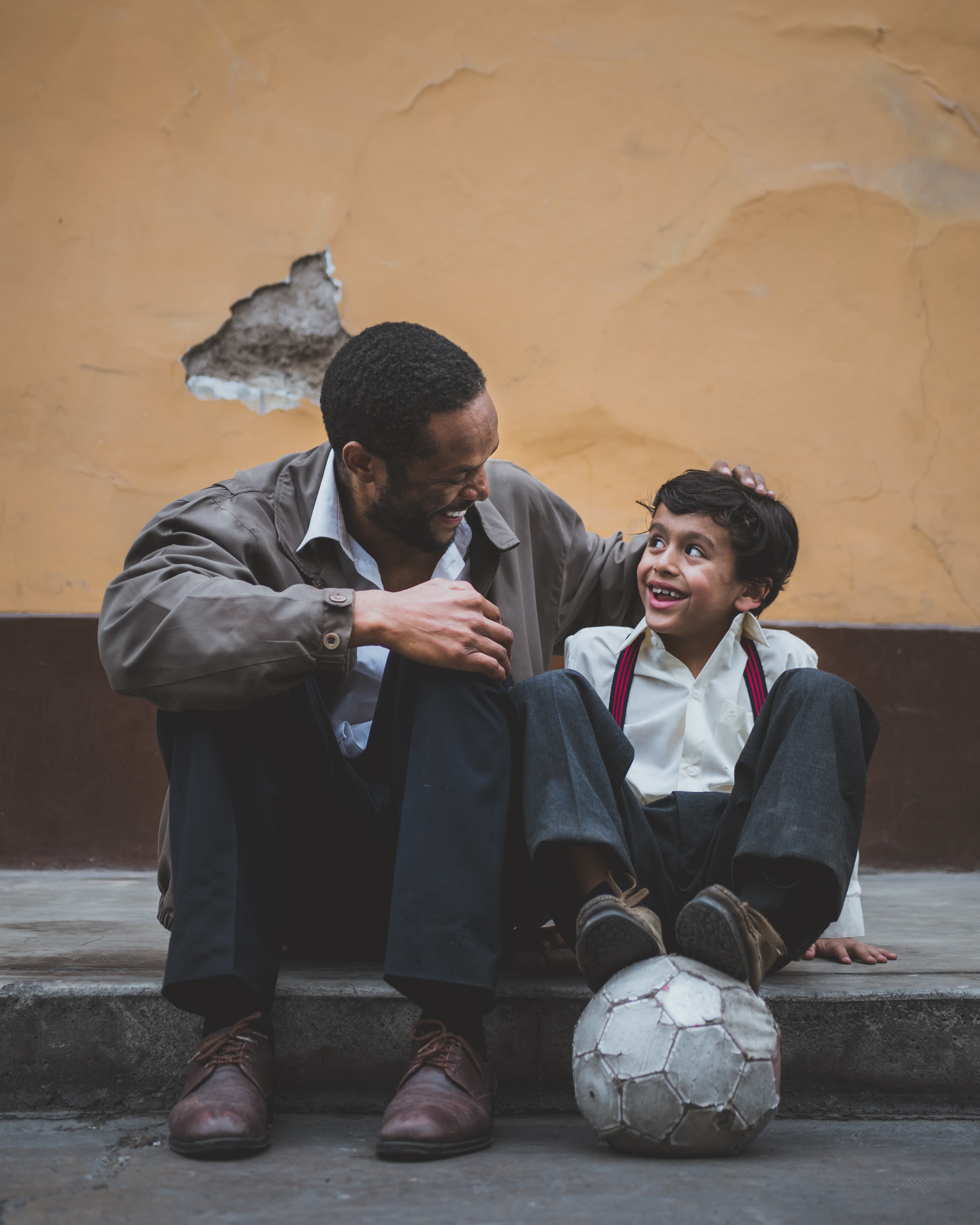 Man and boy sitting on curb smiling