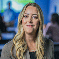 A woman with long blonde hair smiles confidently