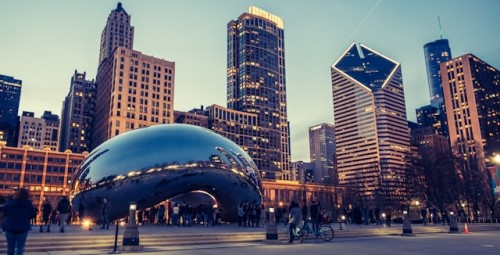 Cloud Gate (The Bean) sculpture in Chicago reflecting the city skyline at dusk.