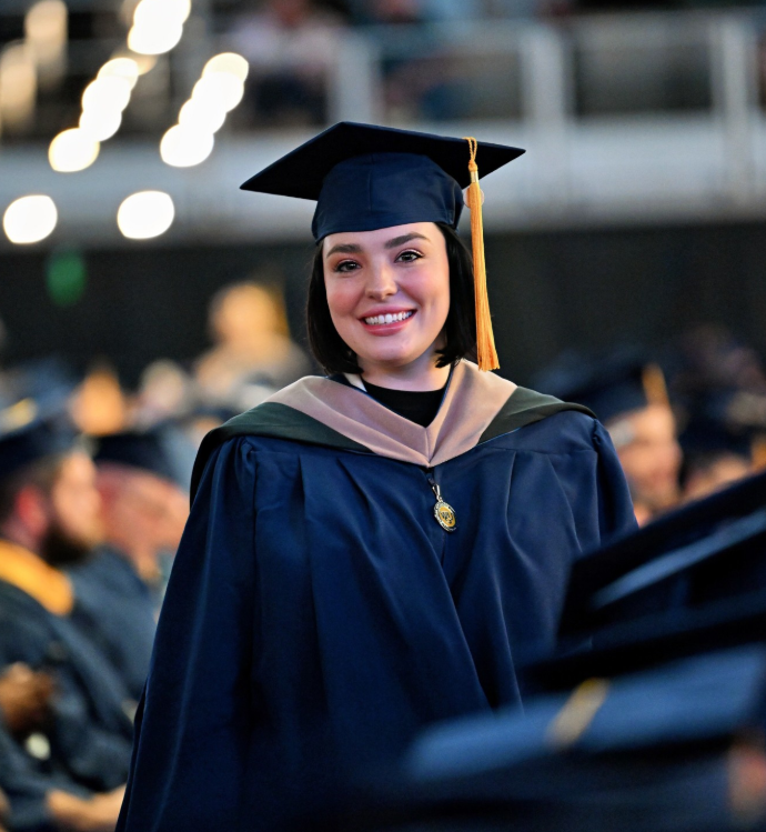 A smiling graduate in a cap and gown.