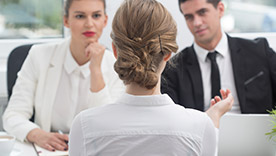 A job interview in progress, with a female candidate facing two interviewers.
