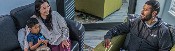 A mother and child sit across from father in a living room.