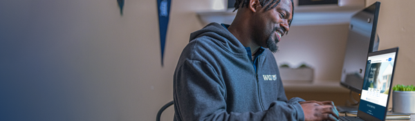 A WGU student sitting at a desk using a laptop computer