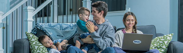 A family sits on a couch with a laptop with a WGU sticker